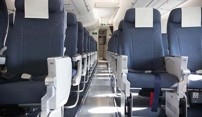 Rows of clean fabric passenger seats and aisle in an airplane cabin