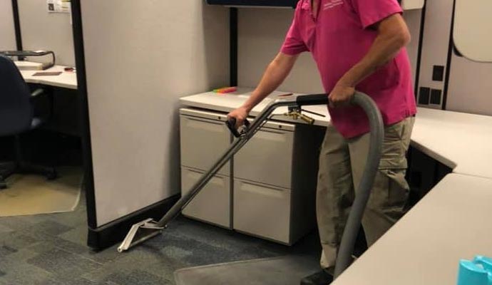A person is cleaning carpet in commercial space