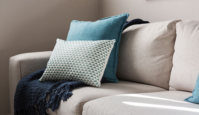 A clean beige sofa with blue and patterned throw pillows