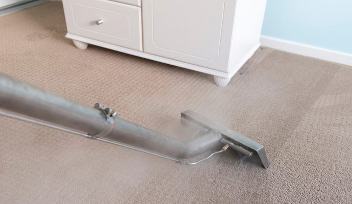 Hot water extraction wand cleaning a bedroom carpet.