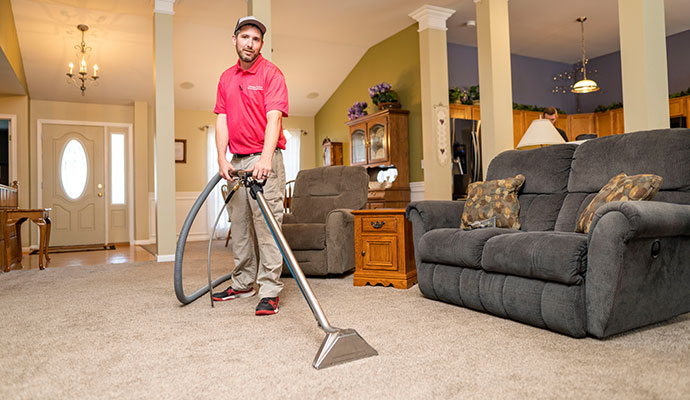 Technician cleaning residential carpet with a steam wand.