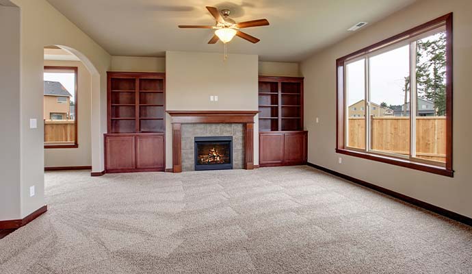 Clean beige carpet in an apartment living room with fireplace and built-in shelving
