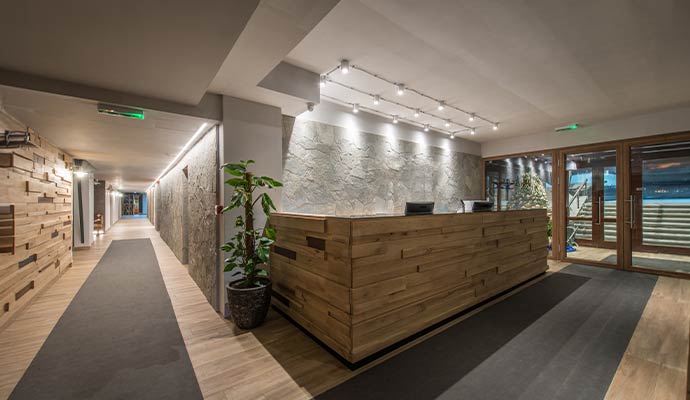 Clean modern commercial lobby with wooden reception desk, elegant lighting and polished interior design