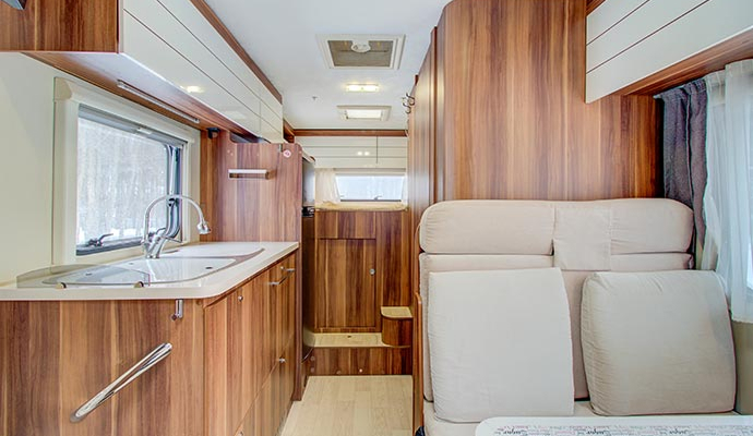 Clean RV interior with compact kitchen and wooden cabinets