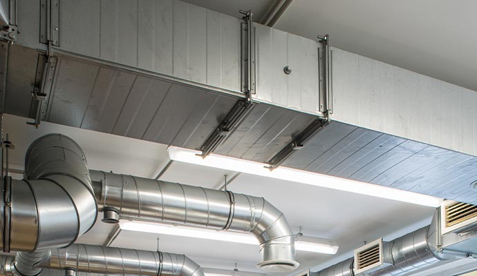 Exposed metal industrial HVAC ductwork and ventilation system in a commercial building ceiling