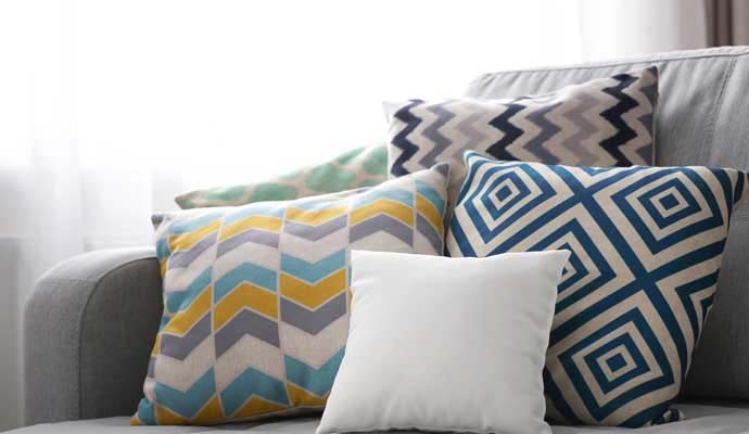 Decorative patterned throw pillows arranged on a grey upholstered couch