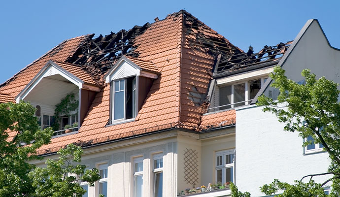 Fire-damaged residential roof with burned rafters requiring restoration.