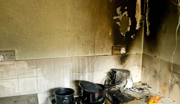 Kitchen wall and countertop with severe smoke and soot damage after a fire.