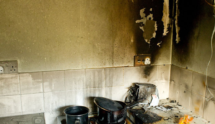 Smoke and soot damage on kitchen wall and countertop after a fire.