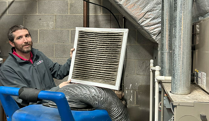Technician holding a dirty, soot-covered HVAC air filter.