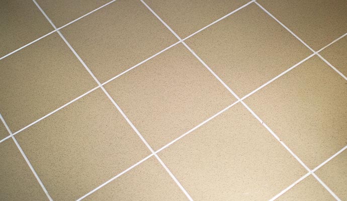 A close-up of perfectly cleaned tan floor tiles and white grout