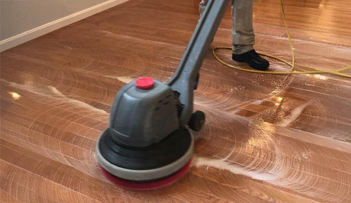 Professional machine cleaning hardwood flooring to restore shine and remove dirt from wood surfaces