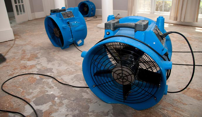 Industrial air movers drying water damaged floor