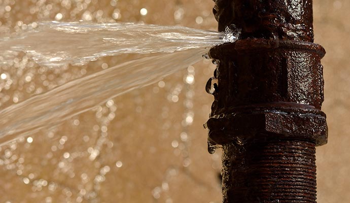 Leaky rusty pipe causing water forcefully spraying out