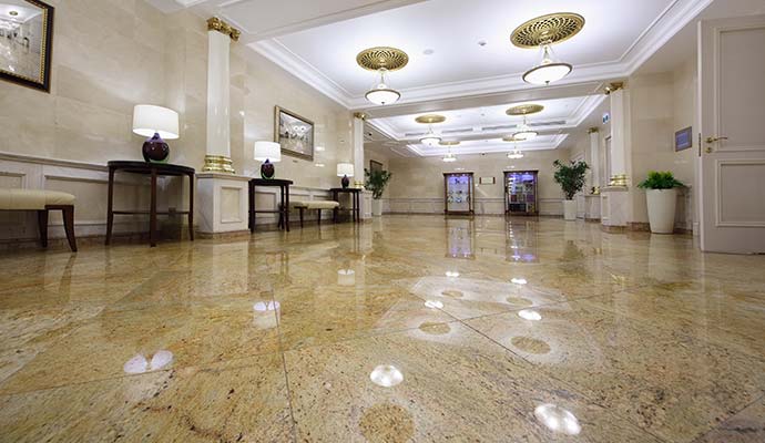 Polished beige granite floor reflecting interior lighting in a commercial building lobby