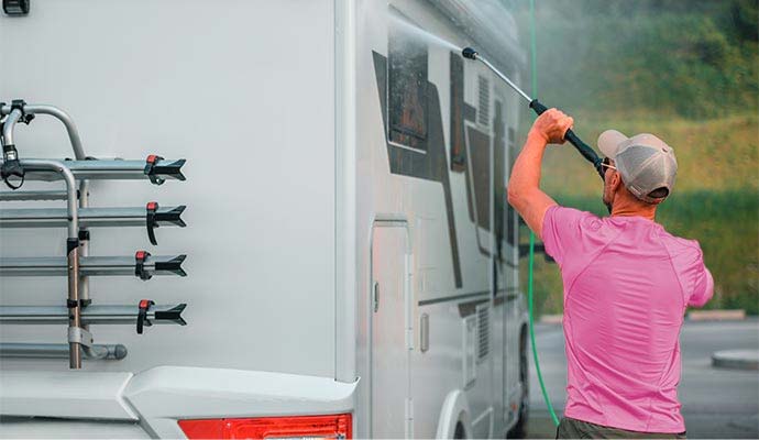 Technician pressure washing the exterior side of a recreational vehicle