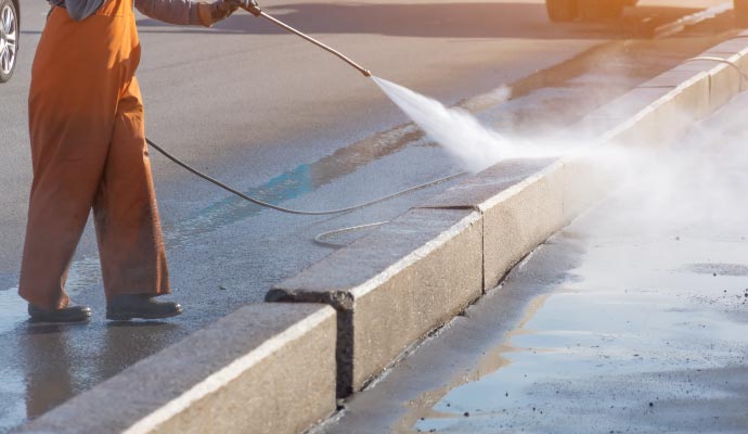 Professional worker soft washing roadside gutter