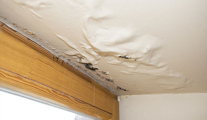 Sagging water damaged ceiling near window