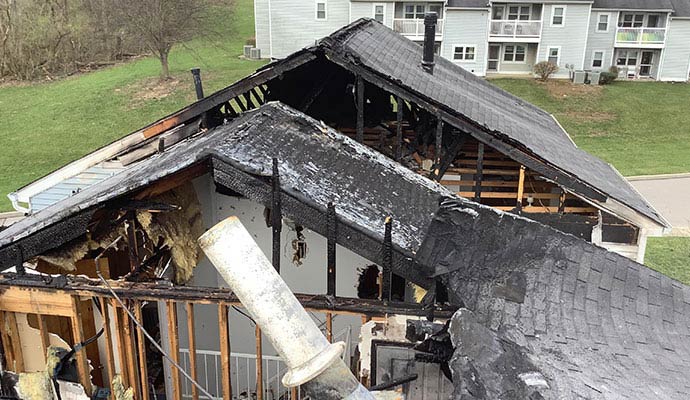 Residential building with severe fire damaged roof exposed framing and collapsed structural sections