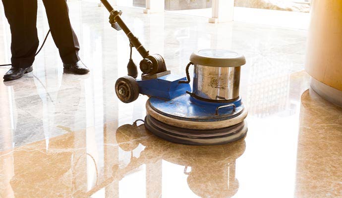 An expert cleaning a stone floor with professional equipment