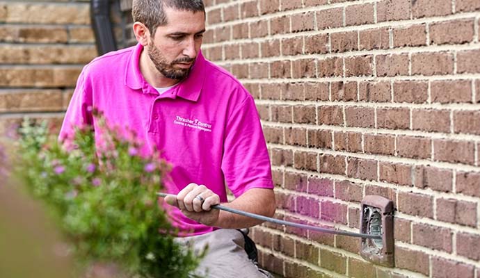 Technician inserting a rotary cleaning brush rod into an exterior dryer exhaust vent