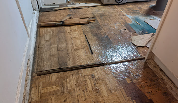 Buckled and water-damaged wood parquet flooring.