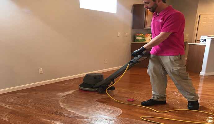 A person is cleaning wooden floor with cleaning machine